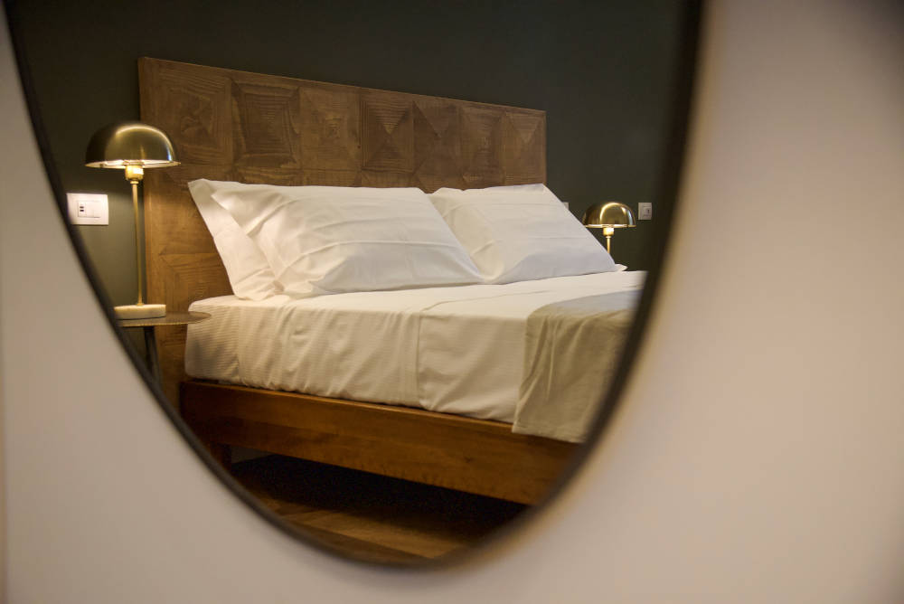 Il letto della stanza superior di Tenuta Acquaviva riflesso in uno specchio